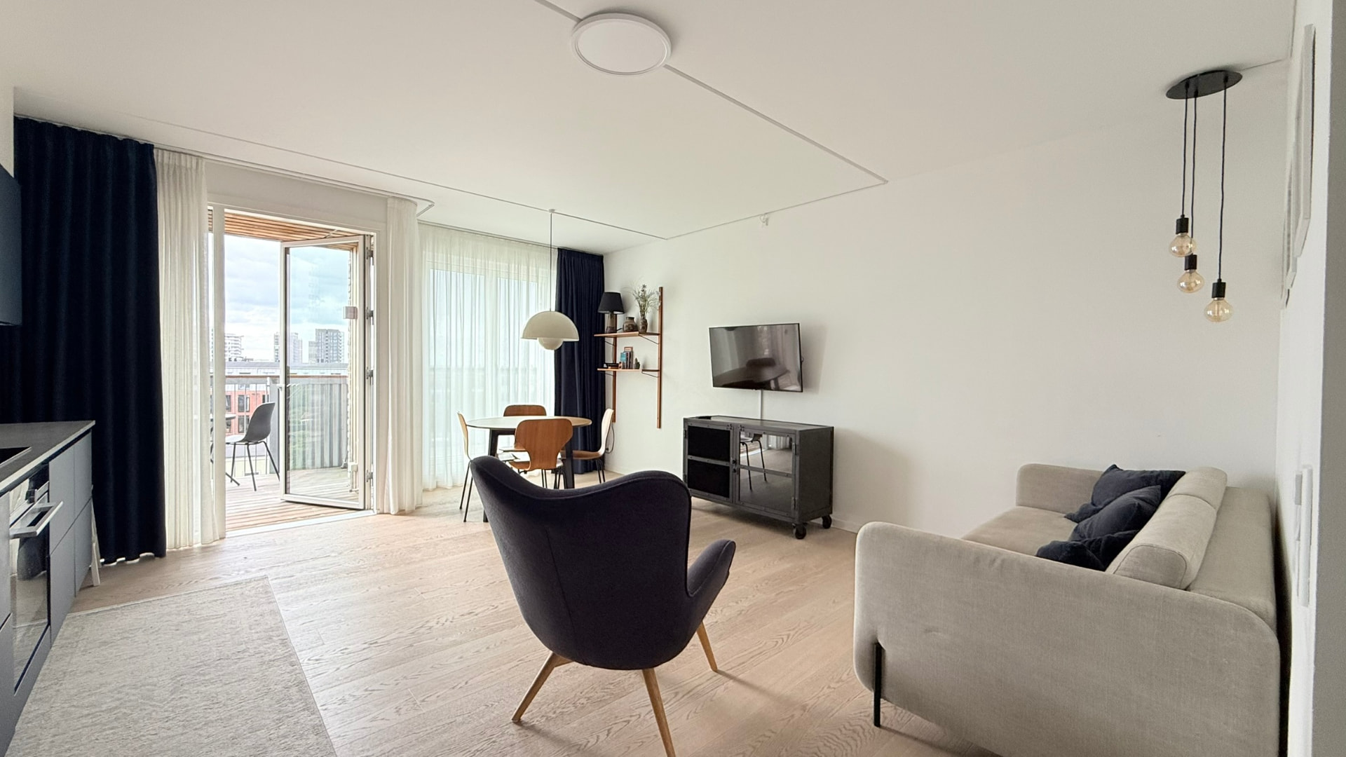 Lys stue med store vinduer og dør ud til egen balkon
